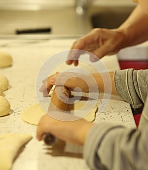 Ð girl rolls out the dough for pies with a wooden rolling pin. The hands of a little girl Ñaucasian close-up. We bake at home.